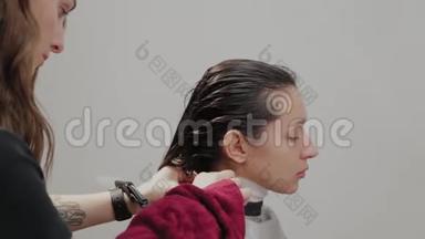 美容美发沙龙。 一个理发师正在用毛巾把客户的头发洗了之后，在水槽里擦拭。